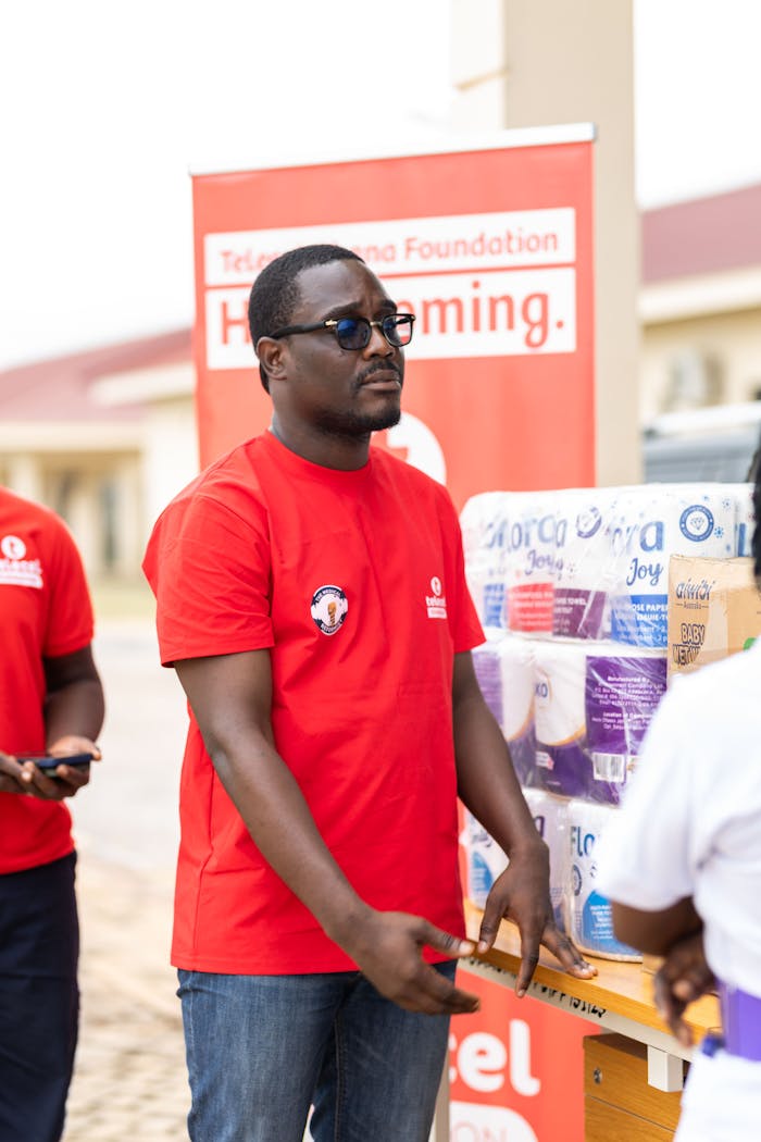 A volunteer in a red shirt handing out supplies during a community outreach event.