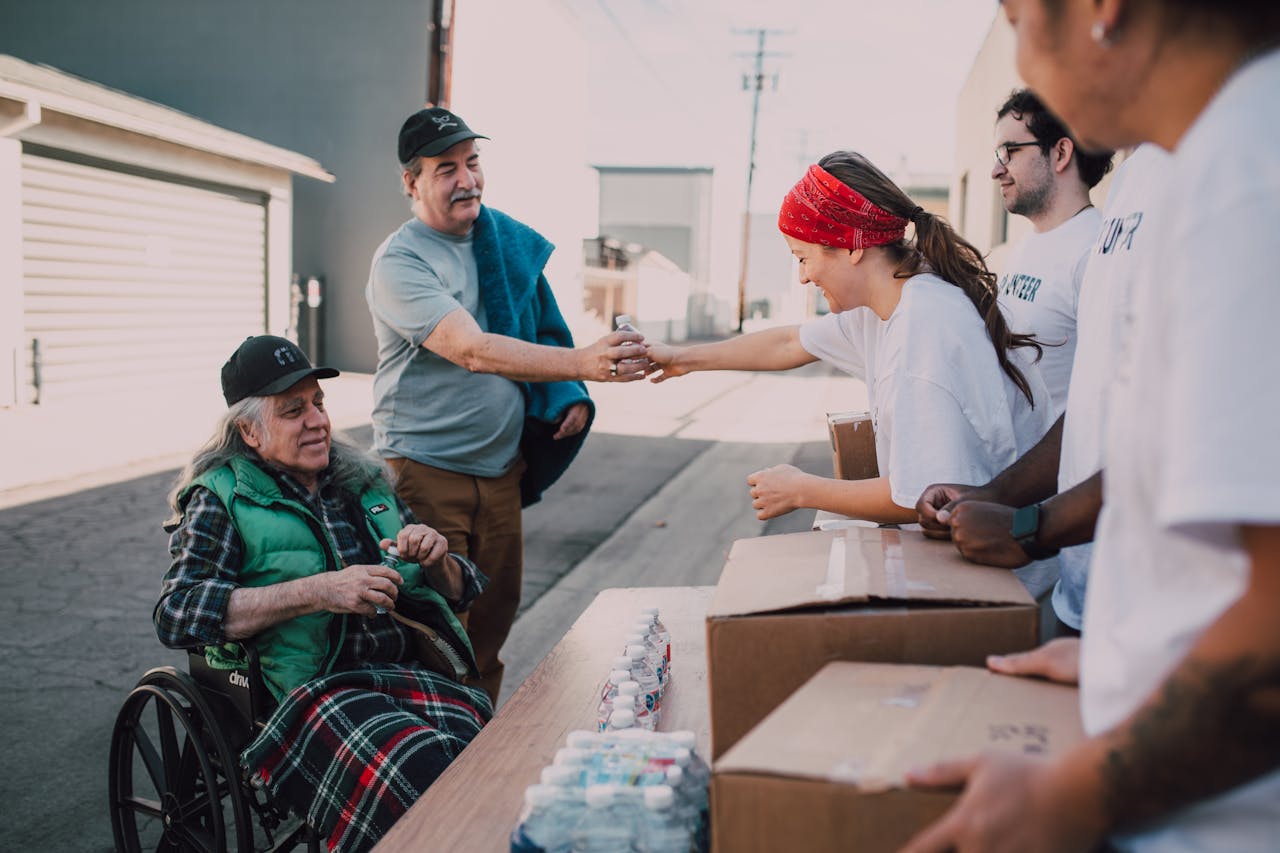 gallery-5 Volunteers distribute water and supplies to people outdoors, promoting community support and kindness.