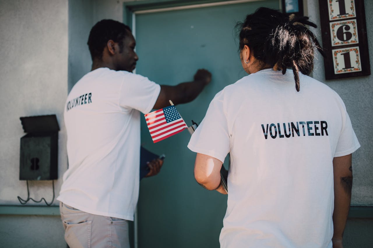 services-03 Two volunteers knocking on door during a community outreach event, holding a small American flag.