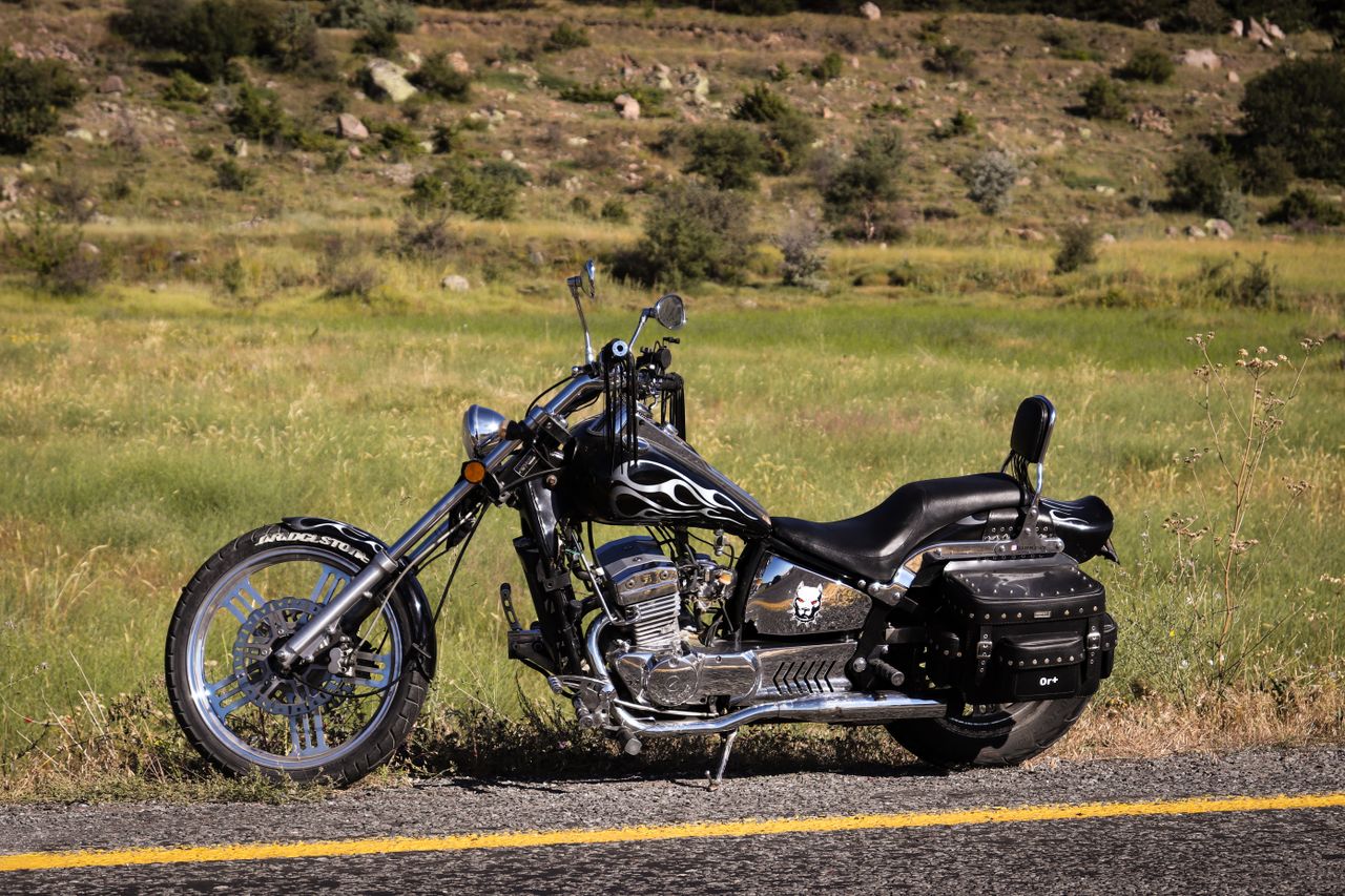 trusted-partner A vintage chopper-style motorcycle with flame design parked on a rural road.